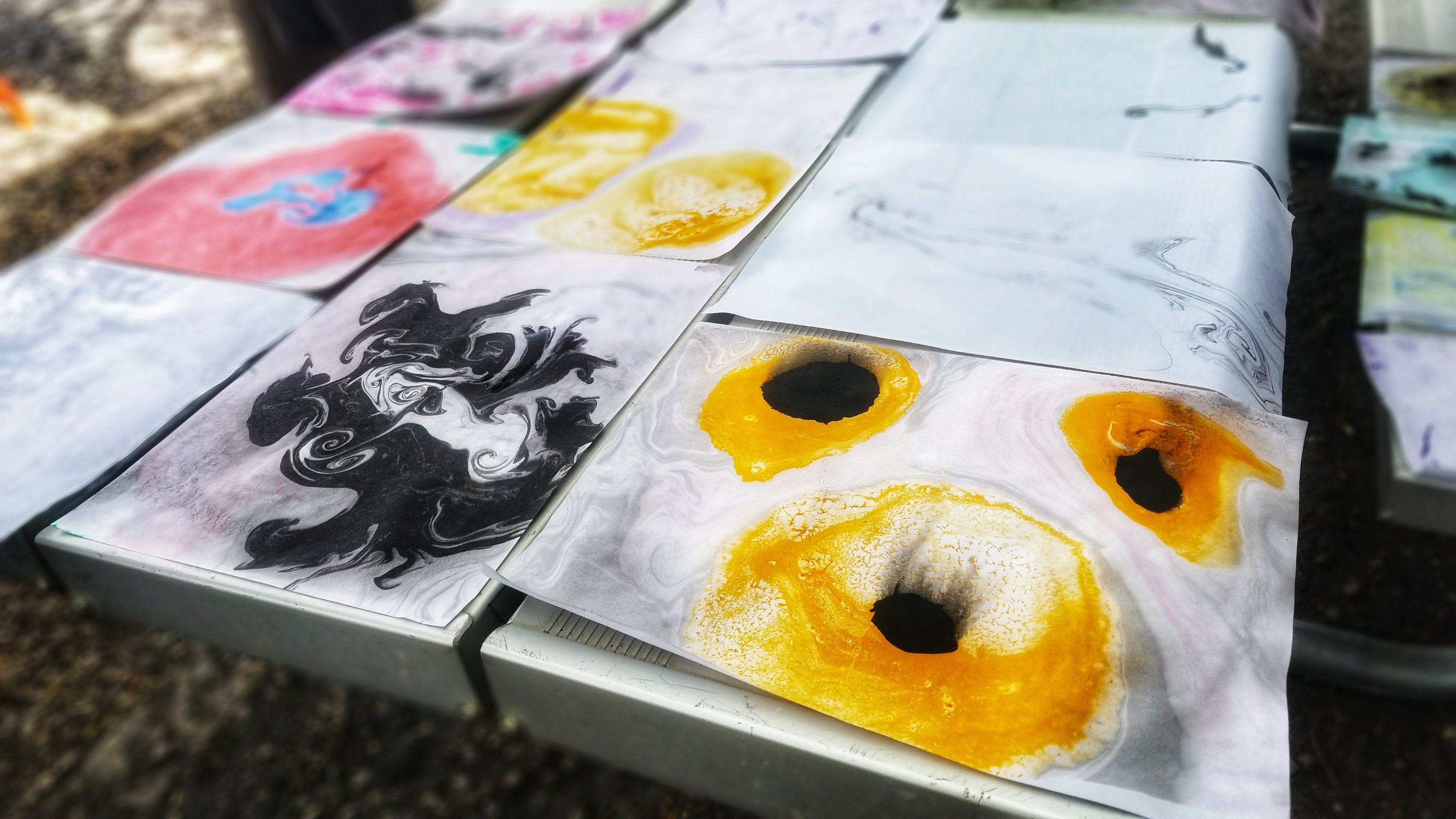 Yellow and black suminagashi drying on a park bench