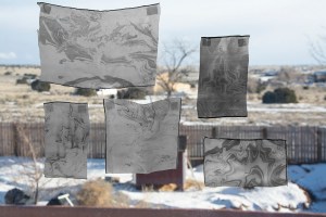 silk fragments taped to a window, each with a unique suminagashi pattern